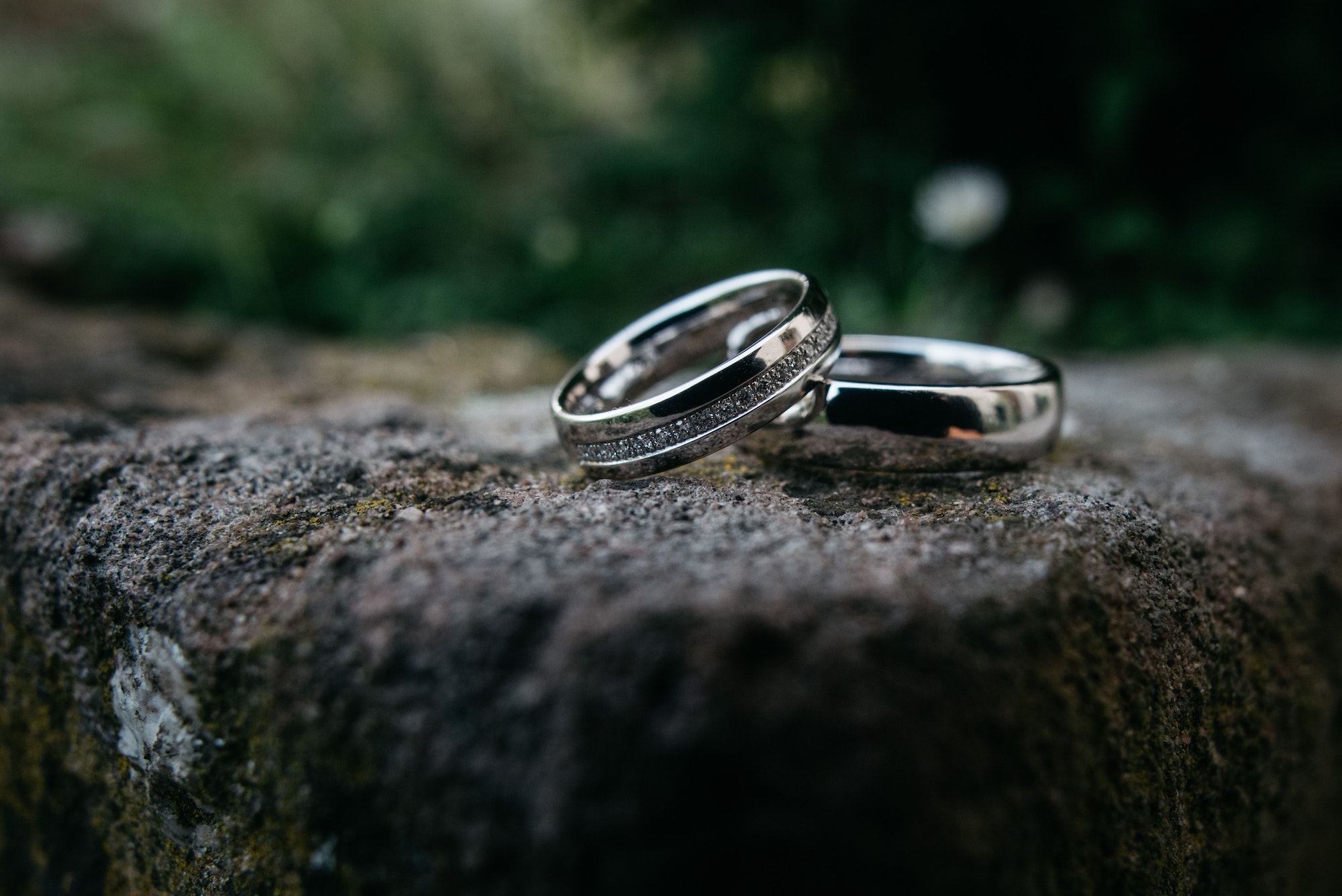 Closeup of wedding silver rings on the stone outdoors blurred background